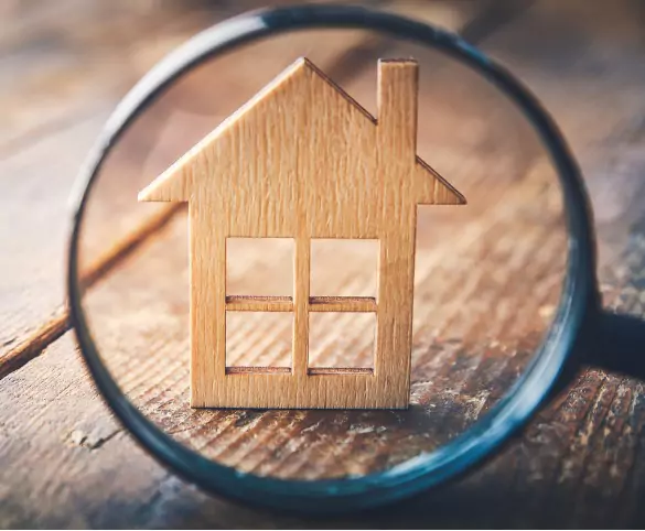 A magnifying glass getting a close look at a wood house, representing the work done by Title Insurance companies in Illinois